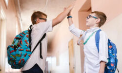 Dos alumnos chocando sus manos en el pasillo de una escuela