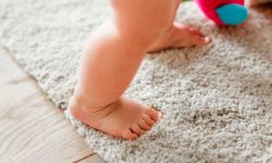 imagen de un bebé dando sus primeros pasos sobre una suave alfombra