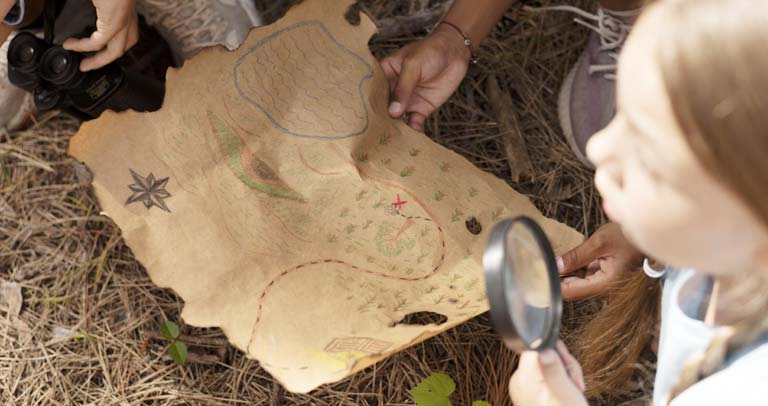 Grupo de niños y niñas en el campo con un mapa del tesoro