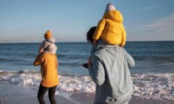 Familia paseando por la playa en invierno