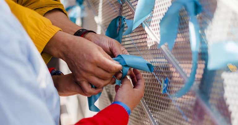 Familia atando un lazo azul durante el Día Mundial del Autismo